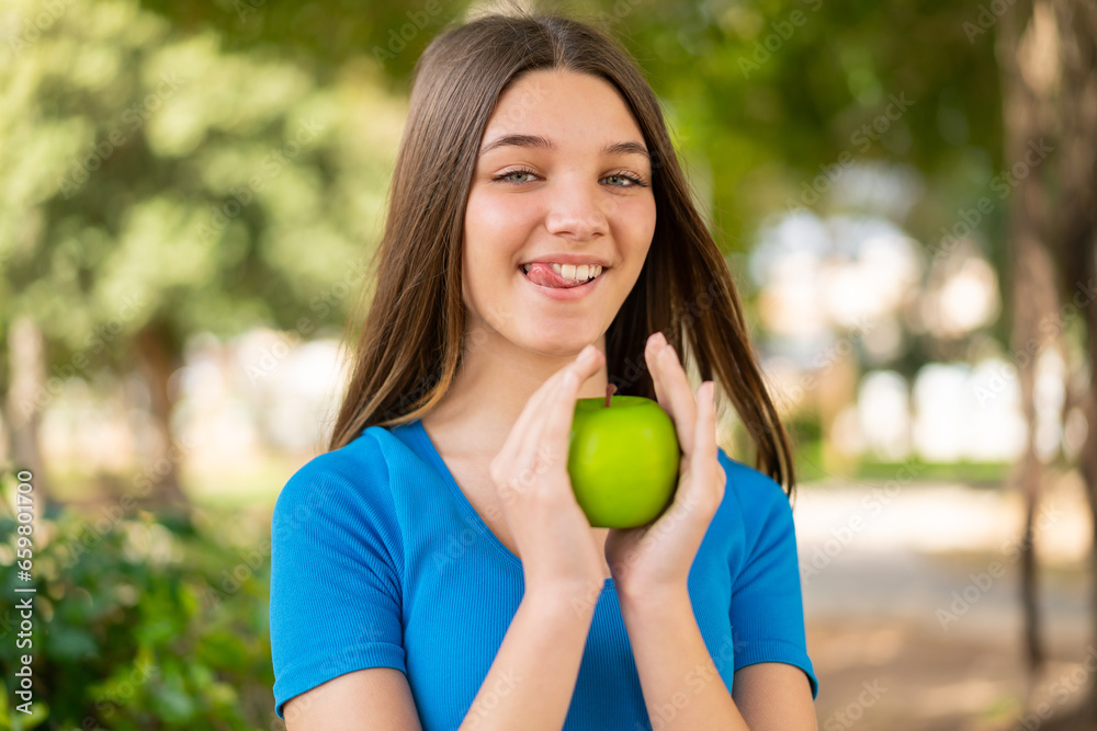 Teenager girl at outdoors holding an apple with happy expression Teenager girl at outdoors holding an apple with happy expression