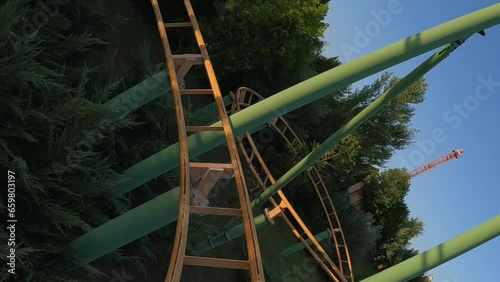 First person view of adrenaline twisting roller coaster at amusement park. Slow motion photo