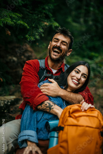 Obraz na plátne A diverse couple, their backpacks suggesting a day of exploration, relaxes on a