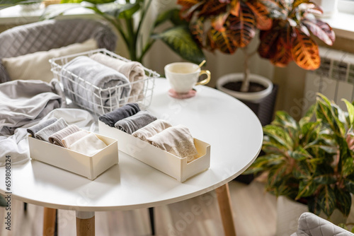 Neatly folded domestic clothes underwear in PVC container and metal grid basket on table