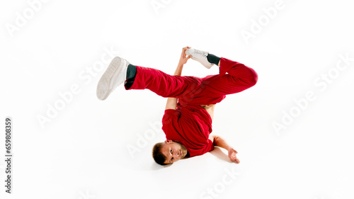 Fashionable portrait. Stylishly dressed young man dancing in freestyle, breakdance style in motion against white background.
