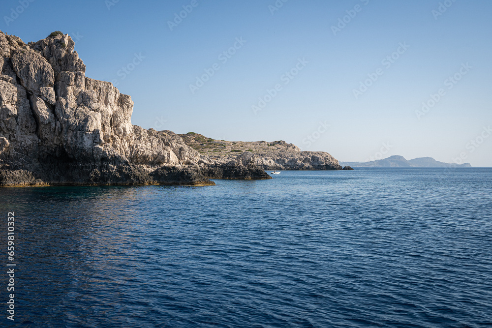 Majestic Rock Formations of Rhodes: A sea-level view of the stunning cliffs and geological wonders along the island's coastline, where the Mediterranean's blue embraces Grecian landscapes. Majestic Rock Formations of Rhodes: A sea-level view of the stunning cliffs and geological wonders along the island's coastline, where the Mediterranean's blue embraces Grecian landscapes.
