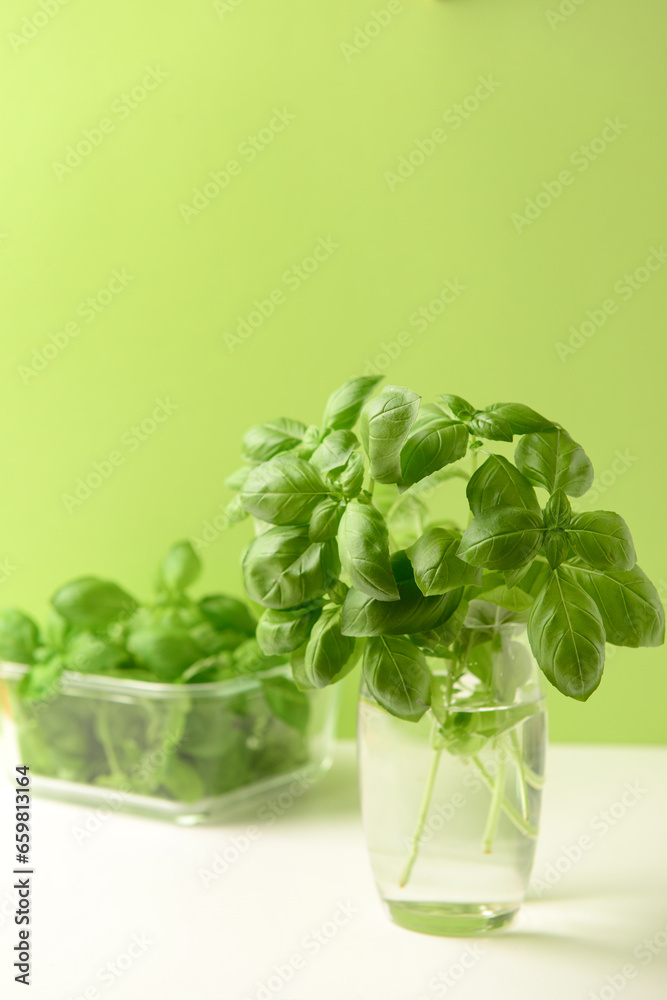 Glass and bowl with fresh green basil on white table Glass and bowl with fresh green basil on white table