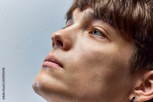 Fresh, male face. Cropped closeup portrait of young attractive brunette man looking away against over grey studio background.