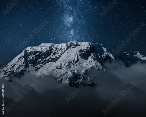 Milky Way above mountains in fog at night in autumn. Landscape with himalayan mountains, low clouds, purple starry sky with milky way 