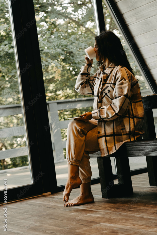 Obraz premium A woman rests and meditates in a house in the forest. Retreat and meditation concept