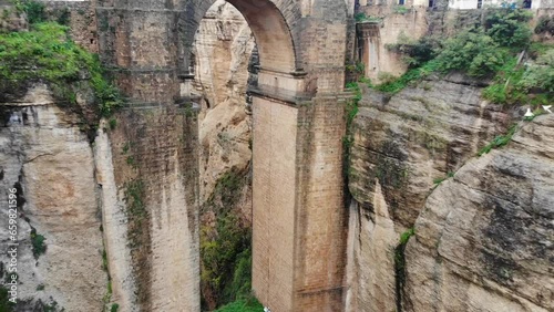 Aerial fly toward arch shot (0:00-0:10) of Puente Nuevo bridge (medieval) and chasm rift in Ronda, Andalusia, Spain. photo