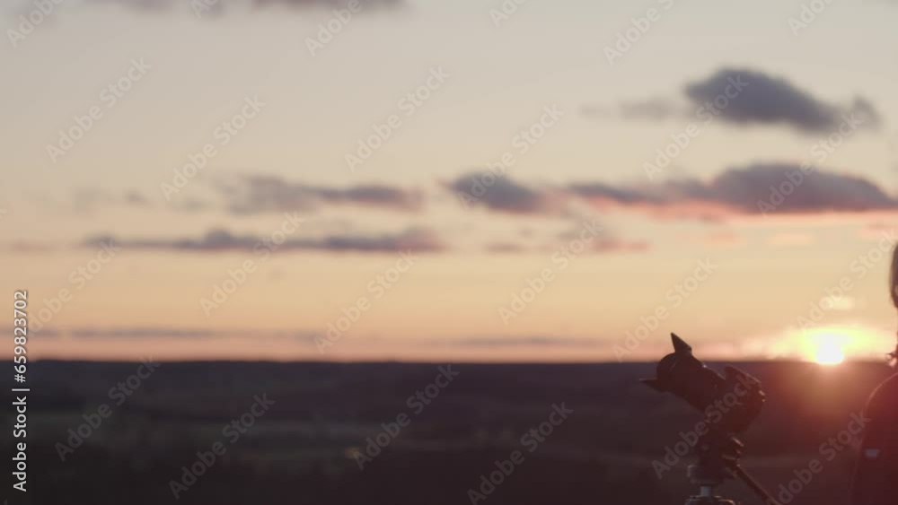 A young female photographer preparing to take pictures of sunset A young female photographer preparing to take pictures of sunset