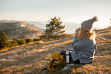 The plus size woman sit on the rop of  the mountain. The gil admires beautiful views of landscape. Travel and tourism. Hiking. The overweight woman drink tea in the nature