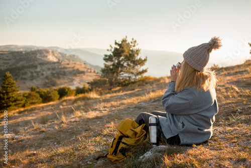 The plus size woman sit on the rop of  the mountain. The gil admires beautiful views of landscape. Travel and tourism. Hiking. The overweight woman drink tea in the nature © Вероника Зеленина