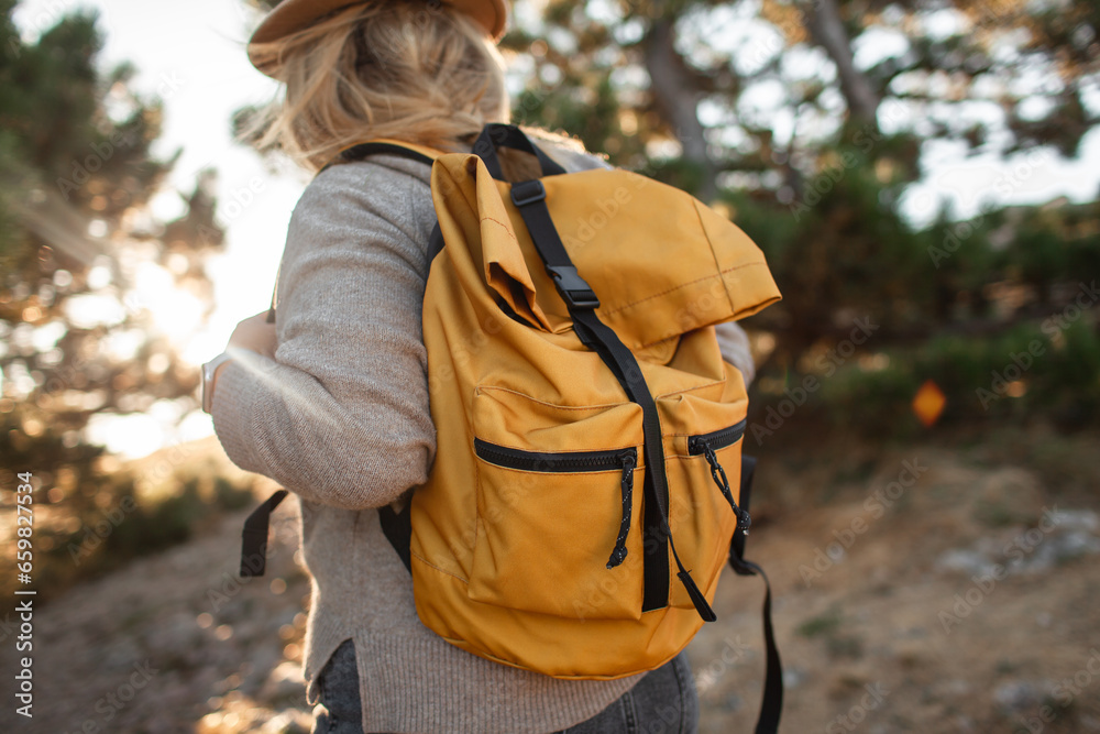 Back view of the plus size woman walks in the mountain. The girl admires beautiful views of landscape. Travel and tourism. Hiking. The overweight woman holding yellow bagpack