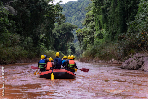 friends and family tourist orange rubber paddle White water rafting in the orange, dangerous, river that flows through the mountains, islands, forests is a fun holiday activity.