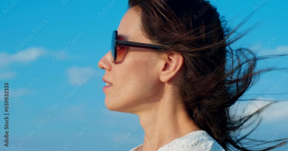 Close-up of young woman face in sunglasses on seashore at sunset, happy and drunk on life, youth and happiness Close-up of young woman face in sunglasses on seashore at sunset, happy and drunk on life, youth and happiness