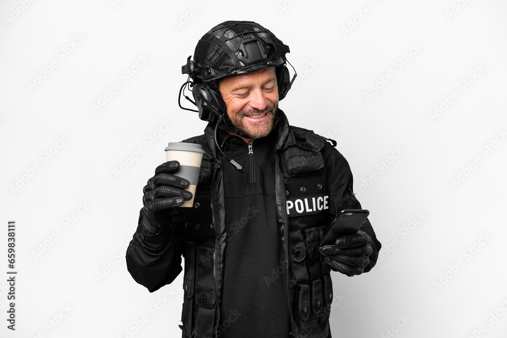 Middle age SWAT man isolated on white background holding coffee to take away and a mobile