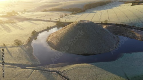 Aerial of Neolithic Silbury Hill, UNESCO World Heritage Site, on a frosty winter morning, with flooding around the mound, Wiltshire, England photo