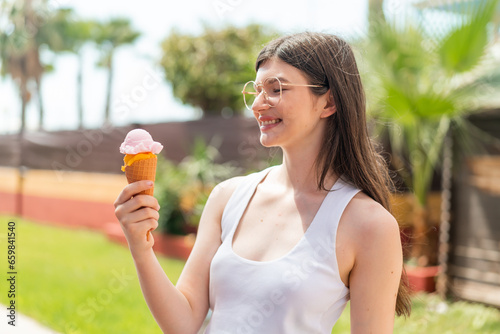 Young pretty Ukrainian woman with a cornet ice cream at outdoors with happy expression