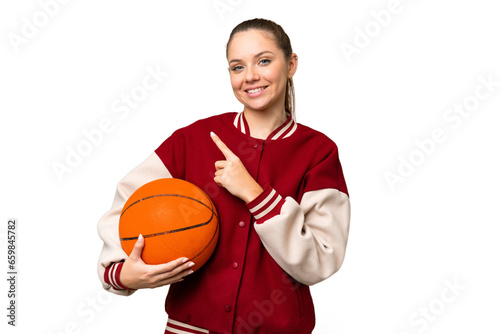 Young blonde woman playing basketball over isolated chroma key background pointing to the side to present a product © luismolinero