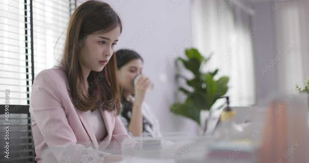 Two Asian business women are sitting and working in office. Teamwork will make success. Work with data technology is good business planning. Drink coffee make you feel refreshed during working day Two Asian business women are sitting and working in office. Teamwork will make success. Work with data technology is good business planning. Drink coffee make you feel refreshed during working day