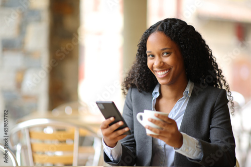 Black executive holding phone and coffee posing