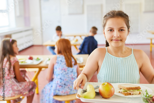 Girl holding tray with healthy food in school cafe
