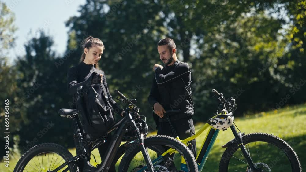 Young Man and Girl Take Off Their Backpacks After Finishing Their Bike Ride. Concept of Healthy lifestyle, Spring or Summer Activity, Bonding, Weekend Activity, Friendship, Recreation, Leisure Young Man and Girl Take Off Their Backpacks After Finishing Their Bike Ride. Concept of Healthy lifestyle, Spring or Summer Activity, Bonding, Weekend Activity, Friendship, Recreation, Leisure