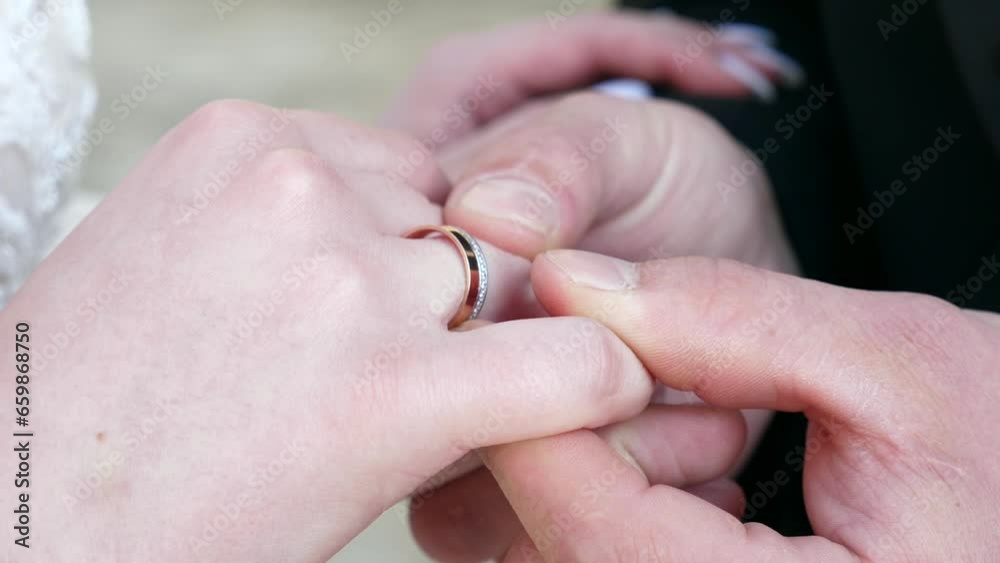 The groom adjusts the wedding ring on the bride's finger. Love and romantic relationships. The groom adjusts the wedding ring on the bride's finger. Love and romantic relationships.