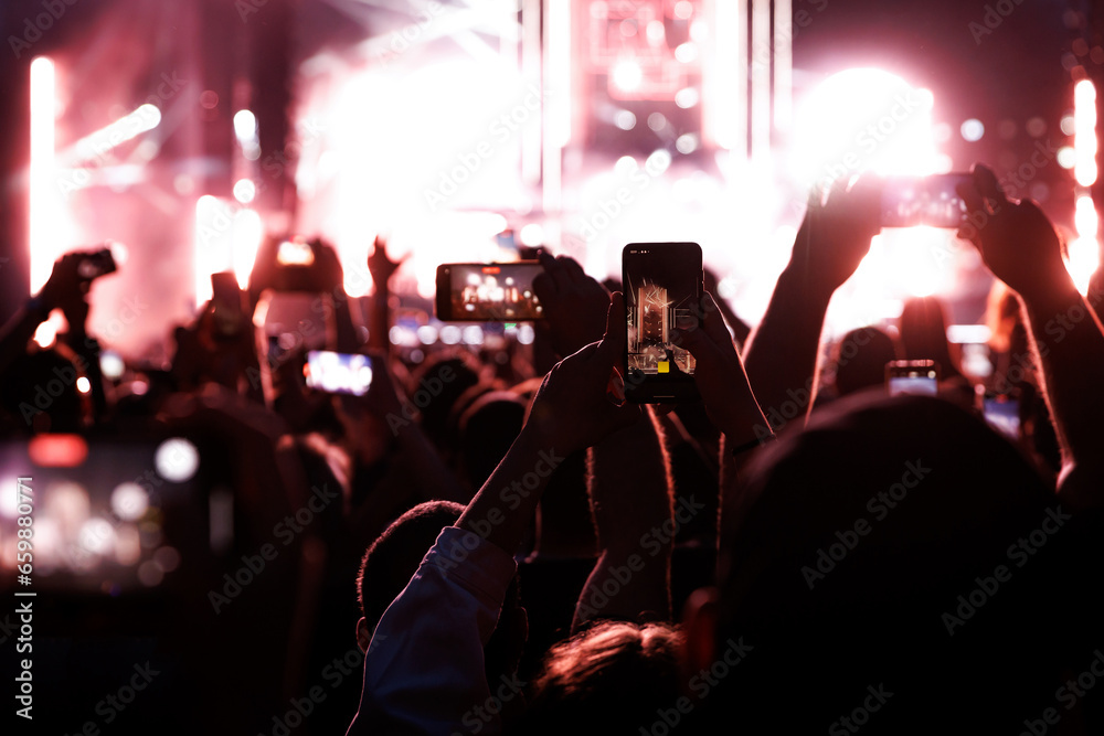 Crowd at a music festival. They are recording the show with their smartphones camera.