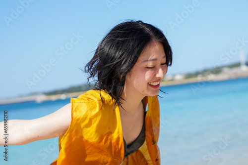 沖縄の砂浜ではしゃぐアジア女性