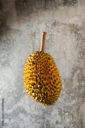 Durian fruit was photographed floating against the background of a cement wall.