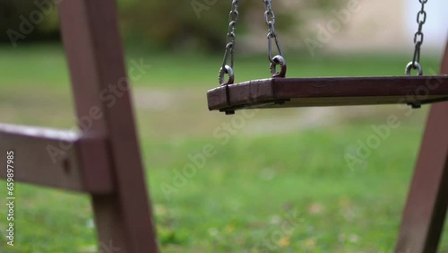 Close up of  empty wooden kids' swing moving in playground or backyard photo