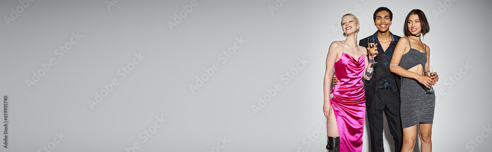 banner, happy african american man hugging multiethnic women in dresses with champagne on New Year banner, happy african american man hugging multiethnic women in dresses with champagne on New Year