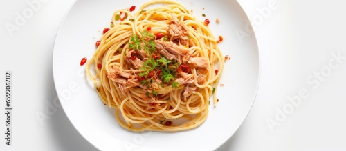 Topped with dried chili and garlic canned tuna spaghetti on a white plate presenting fusion cuisine from a bird s eye view With copyspace for text