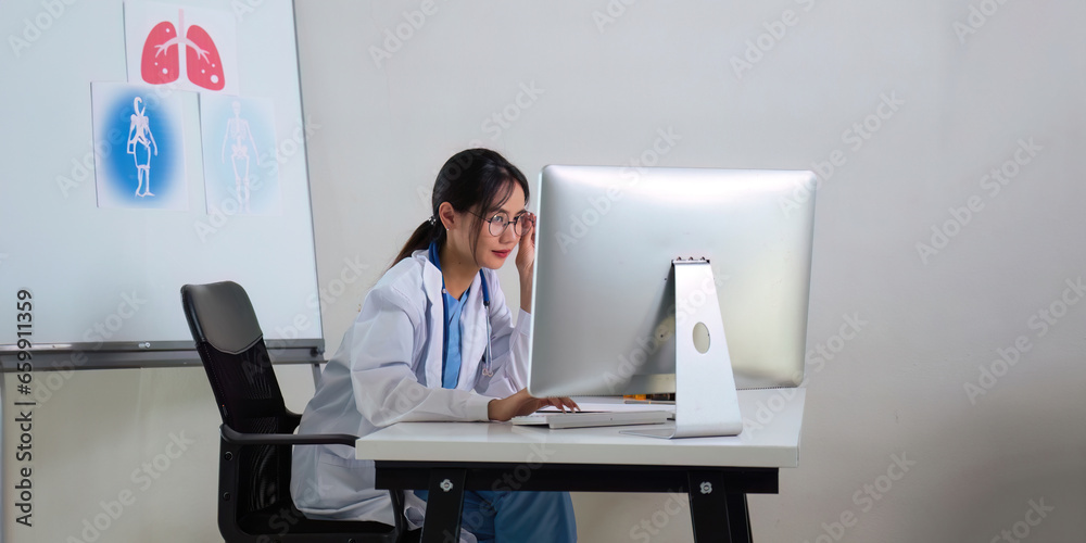 Female doctor a works at a computer while there were many medicine bottles on the table while sitting at a work desk Female doctor a works at a computer while there were many medicine bottles on the table while sitting at a work desk