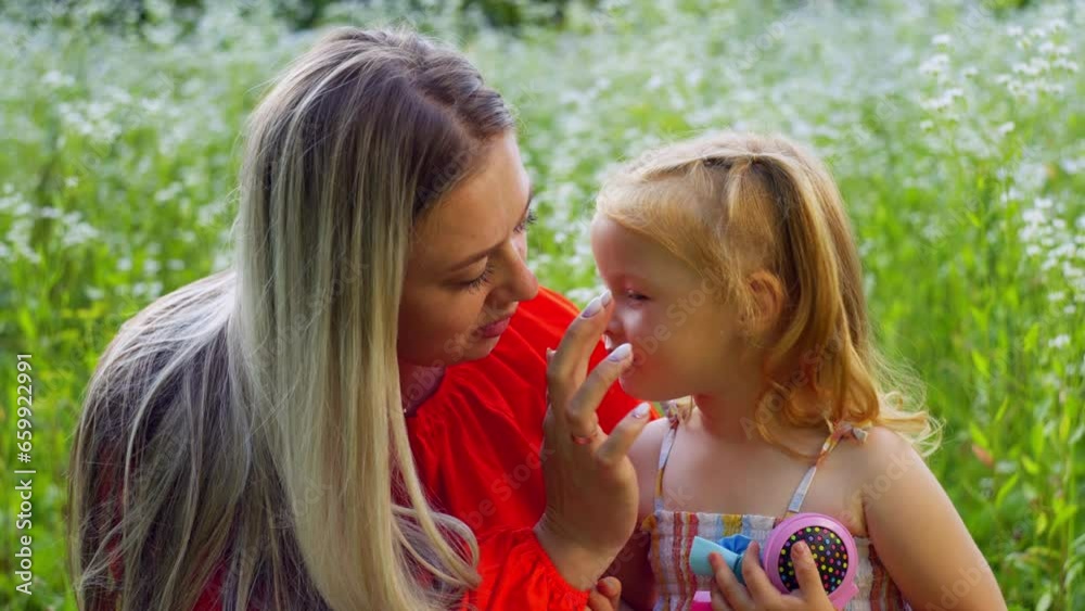 Mom carefully smears glitter on her daughter's face. The child is happy and satisfied with the time spent. High quality 4k footage Mom carefully smears glitter on her daughter's face. The child is happy and satisfied with the time spent. High quality 4k footage