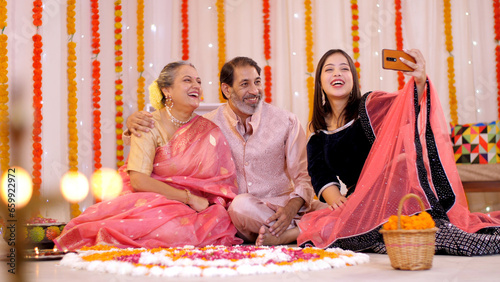 Photography Adorable Indian family taking selfies or self photographs at home -  colorful  decorated background  Festive season