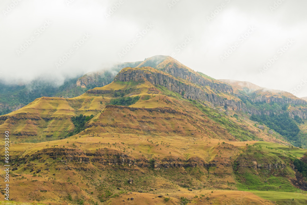 Sunlight beginning to break through the mist hanging over the Drakensberg mountains, near Cathedral Peak in KwaZulu-Natal, South Africa