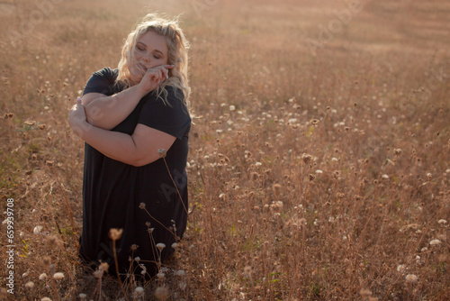 Portrait of beutiful plus size woman walks outdoor against the field and sunloght photo