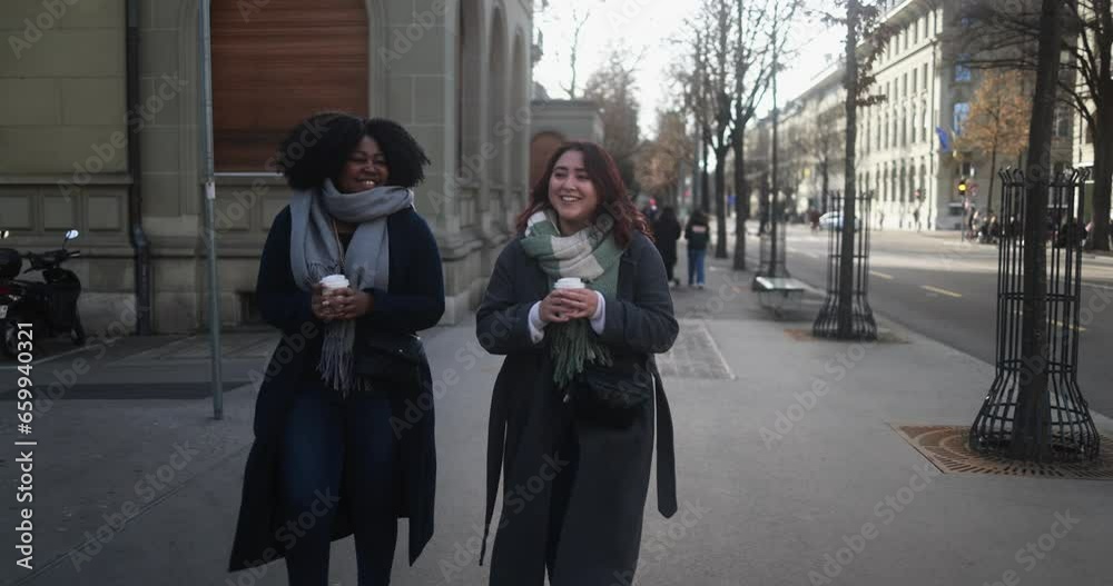 Multiracial women walking in the city with take away coffee cup during winter time 