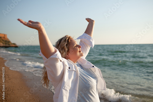 Plus size woman walking in the beach. The overweight woman raised her hands up and enjoy the sea breeze. Happy moment