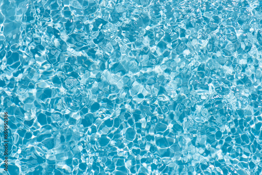 Obraz premium Bluewater waves on the surface ripples blurred. Defocus blurred transparent blue colored clear calm water surface texture with splash and bubbles. Water waves with shining pattern texture background.