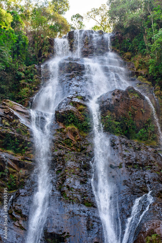 Waters from a waterfall running down a large rock through rainforest vegetation in Minas Gerais  Brazil