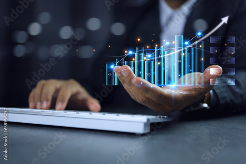 Business finance investment concept. Businessman hand holding bar chart and using computer to analysis the marketing data information economic growth direction with market trend