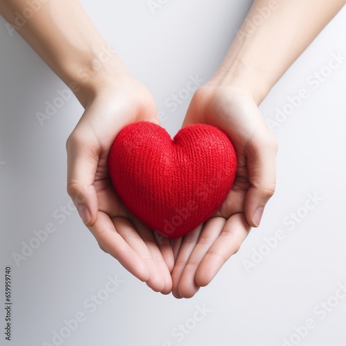 hands hold a red heart on a white background.