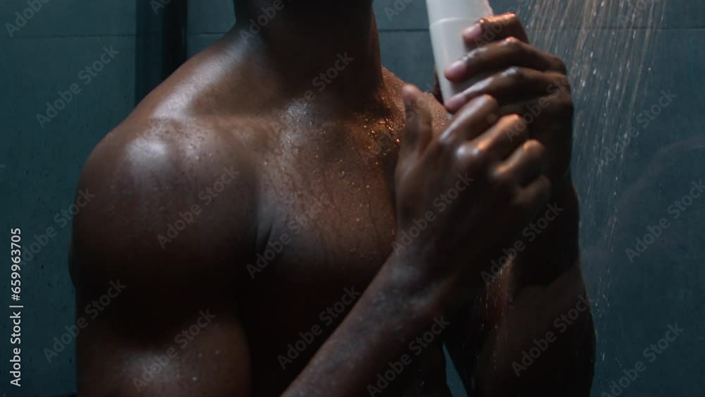 African American man singing in bathroom having fun carefree happy ethnic muscular athletic male energy dancing to music sing with bottle shampoo shower gel refresh bodycare morning bathing hygiene 