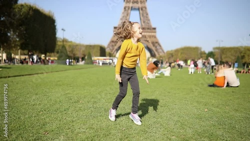Adorable happy preschooler girl having fun near the Eiffel tower in Paris, France