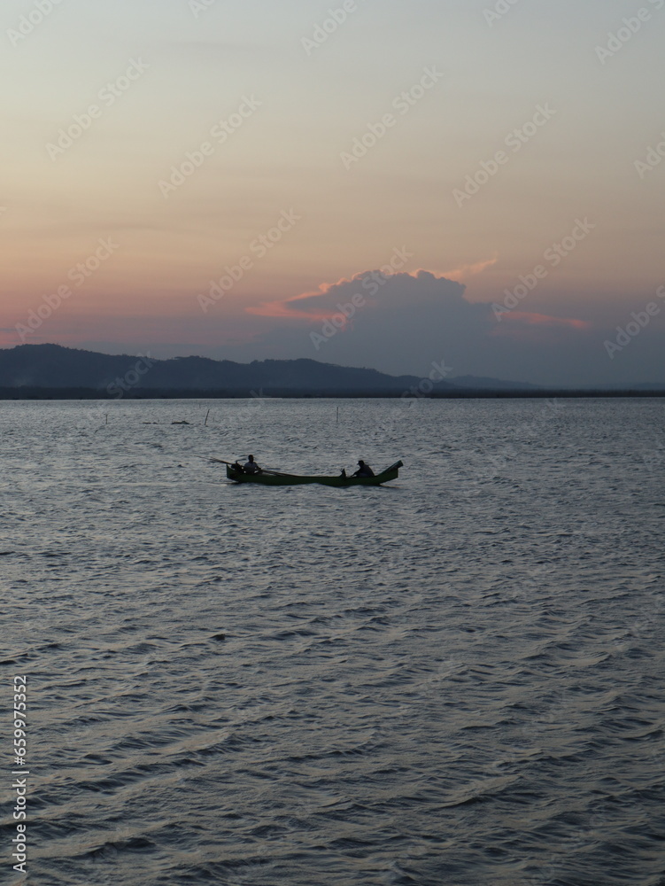 silhouette of fisherman on the lake at sunset
