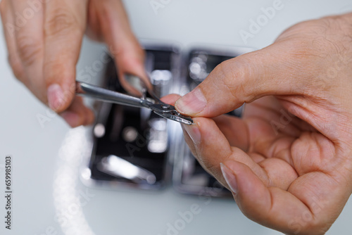 Men's hands manicure with professional clippers. A man gives himself a manicure