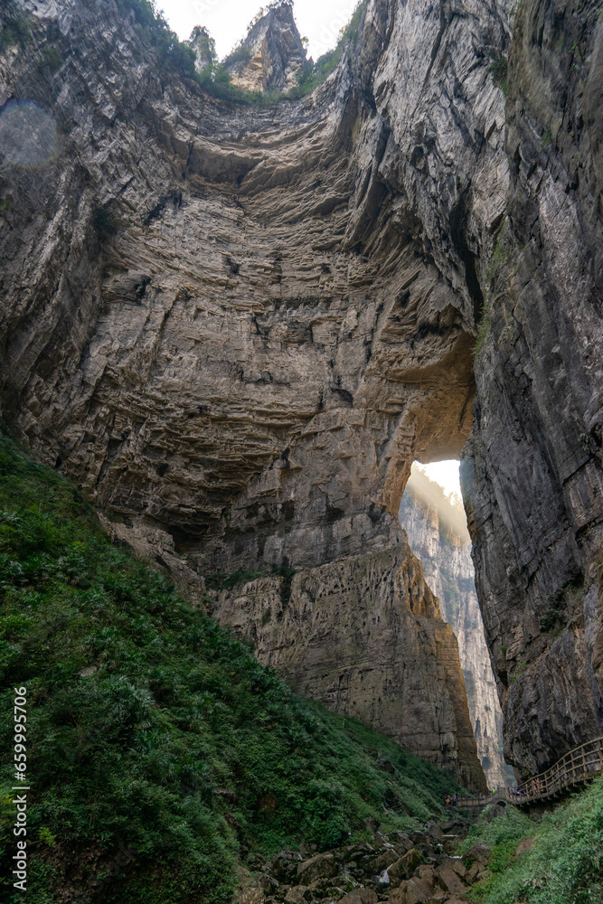An imposing and majestic cliff dominates the landscape of Wulong Karst in Chongqing, China. This natural wonder stands as a testament to the raw, awe-inspiring beauty of karst topography
