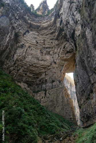 An imposing and majestic cliff dominates the landscape of Wulong Karst in Chongqing, China. This natural wonder stands as a testament to the raw, awe-inspiring beauty of karst topography