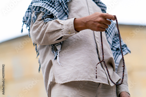 Male hands of an Islamic man holding rosary during prayer of conversion and worship of Allah